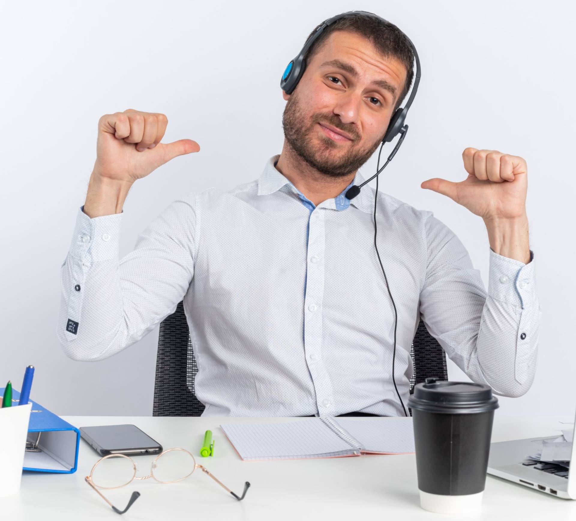 Person at a desk with headphones gesturing thumbs down.